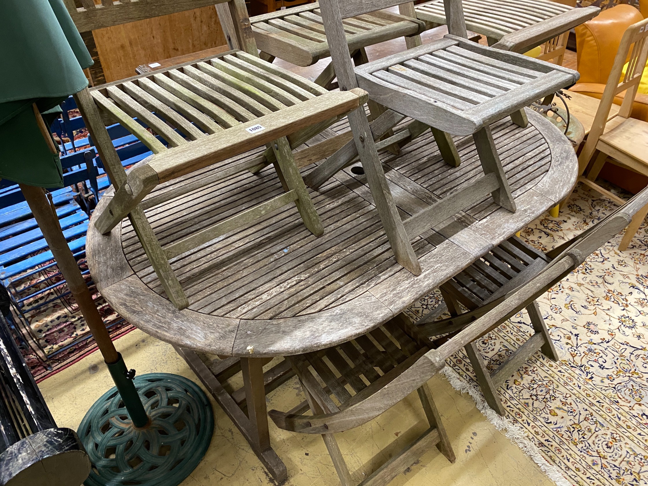 A weathered teak extending garden table, length 170cm, width 100cm, height 74cm parasol with cast metal base and six folding chairs (four and two)